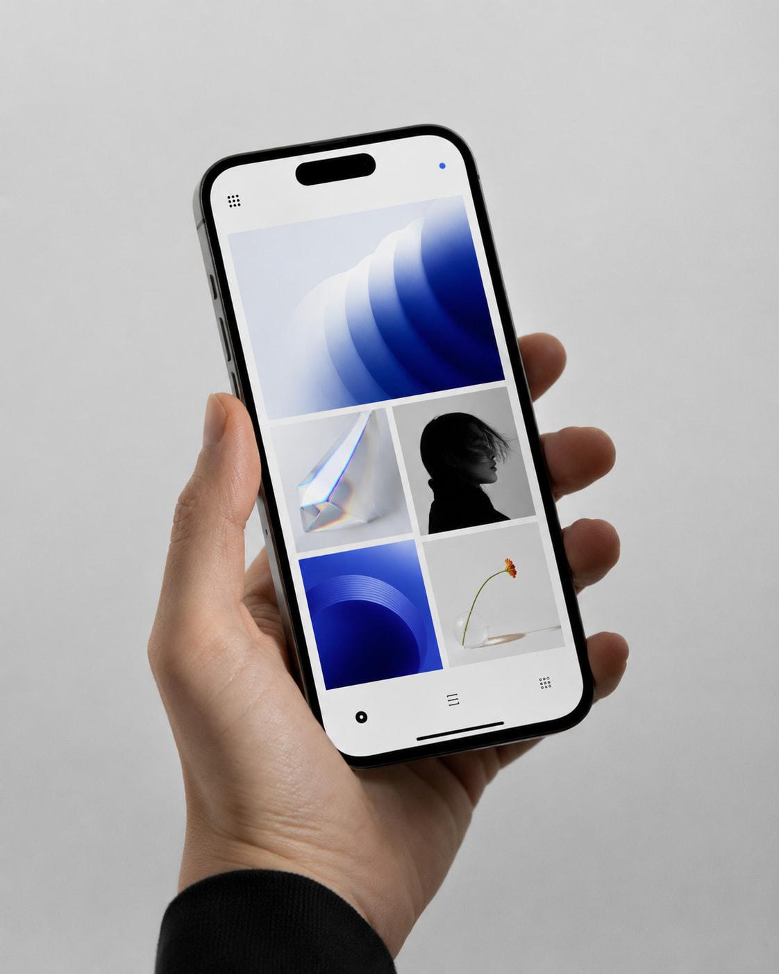 A hand holding a phone, its screen filled with a grid of blue and monochrome images.